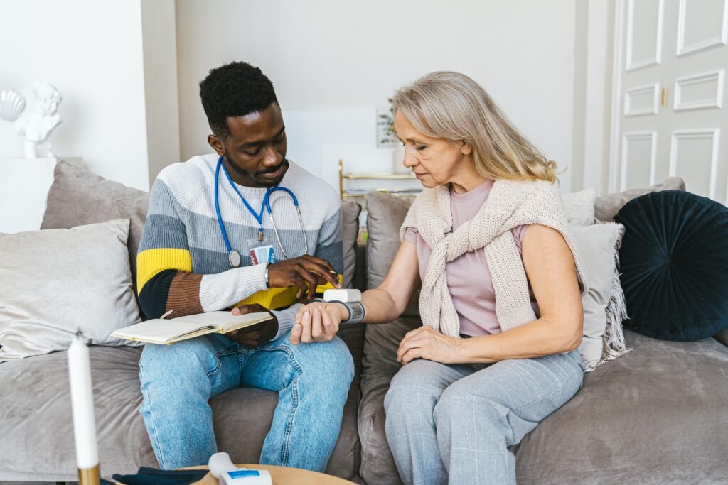 Healthcare professional checking blood pressure of elderly woman in a cozy indoor setting.